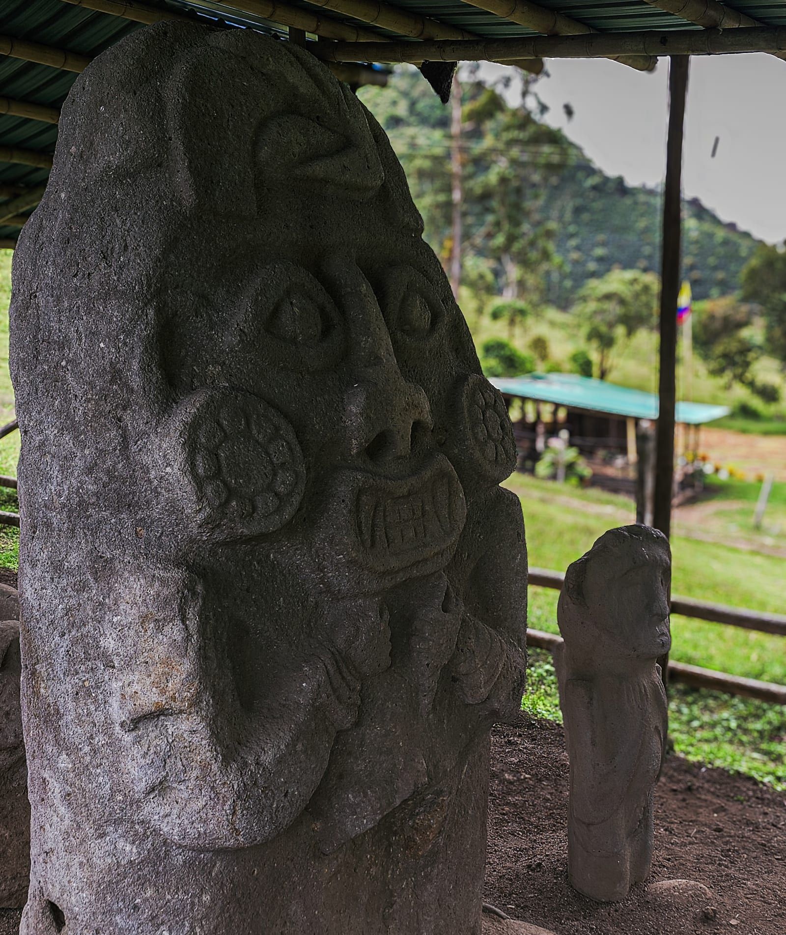 Guardián de piedra tallada en Vegonia Arqueológica: ojos almendrados, dientes tallados y tocado con ave, tradición del Alto Magdalena